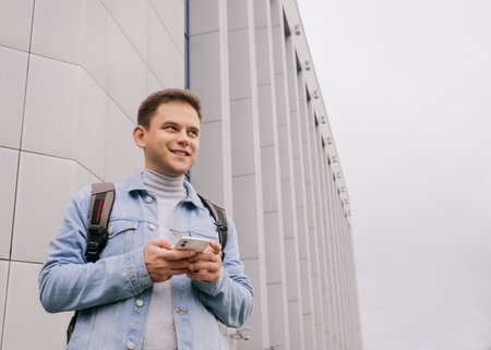 urban lifestyle. Photo with copy space. Young smiling man with cell phone standing outdoorの写真素材