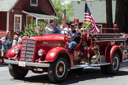 Graeagle, California, USA- July 5, 2015: Firemen aboard a vintage fire engine driving in a parade smile and wave at the crowd during the Mohawk Valley Independence Day Celebration,.のeditorial素材