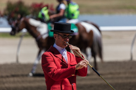 Bugler in top hat and coat plays Cal to the Post at the horse races in Sacramento, California.