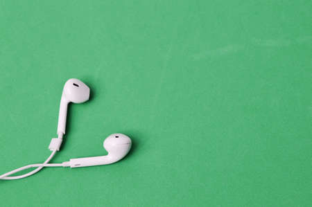 White earphone isolated on a green backgroundの写真素材