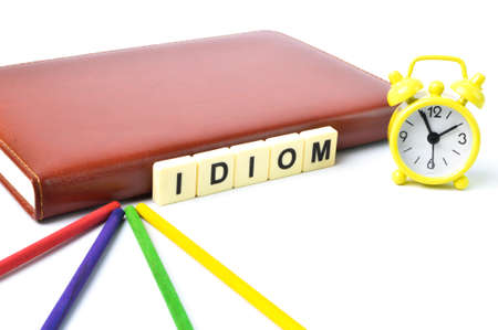 Selective focus of clock, notebook, wooden sticks and letters with text IDIOM