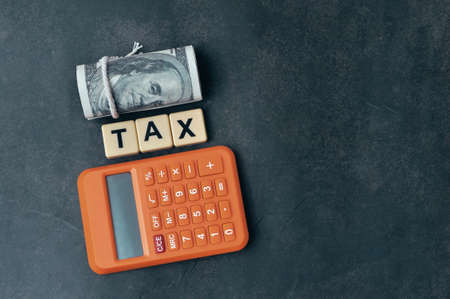 Top view of money banknote, calculator and square letters with word TAX