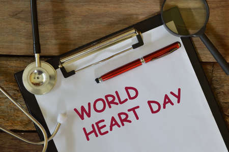 Top view of white paper written with WORLD HEART DAY over wooden background.の写真素材