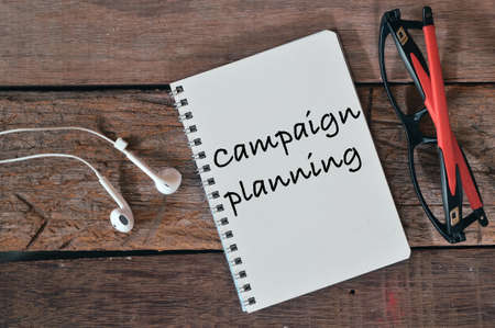 Top view of earphones, eyeglasses and notebook written with text CAMPAIGN PLANNING.の写真素材
