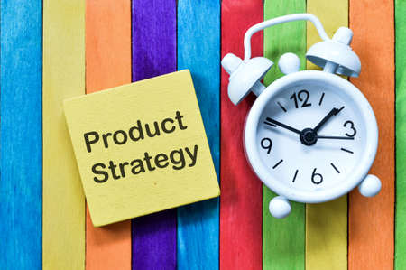Top view of clock and wooden block written with PRODUCT STRATEGY.