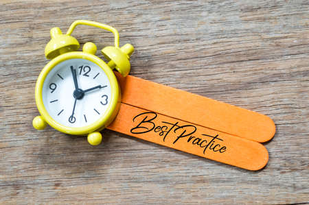 Top view of clock and ice cream sticks written with text BEST PRACTICE.の写真素材