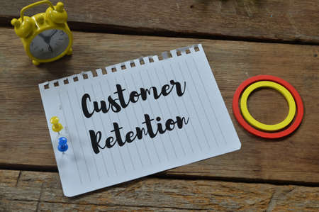 Top view of white paper written with text CUSTOMER RETENTION over wooden background.の写真素材