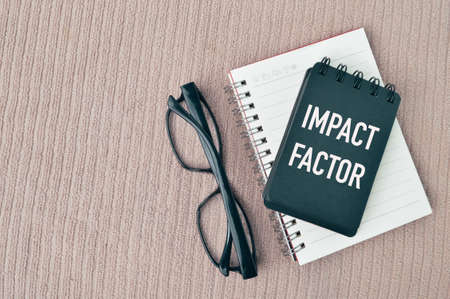 Top view of eyeglasses and notebooks written with text IMPACT FACTOR.の写真素材