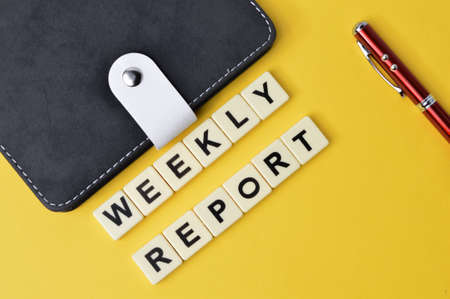 Top view of pen, notebook and square letters with text WEEKLY REPORT.の写真素材