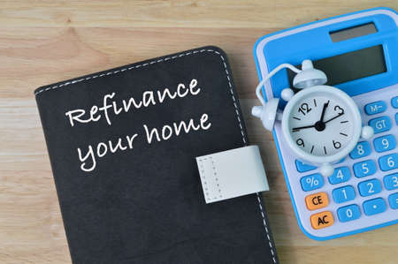 Top view of clock, calculator and notebook written with text REFINANCE YOUR HOME.の写真素材