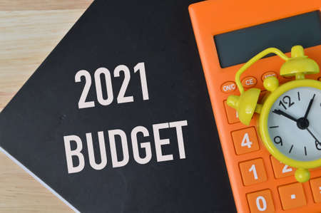 Top view of clock, calculator and notebook written with text 2021 BUDGET.の写真素材