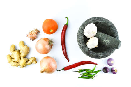 Top view of pestle and mortar with the onions, garlic, red chilies, green chilies, ginger and tomato isolated on a white background.の写真素材