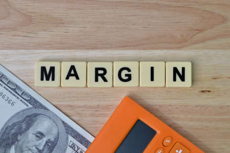 Top view of money banknote, calculator and square letters with text MARGIN.の写真素材