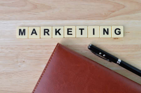 Top view of pen, notebook and block letters with text MARKETING.の写真素材