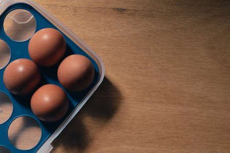 Top view of chicken eggs in box over wooden background. Selective focus.