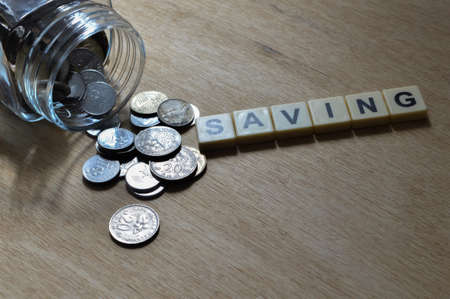 Stack of coins and square letters with text SAVING.の写真素材