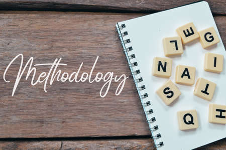 Square letters, notebook over wooden background written with METHODOLOGY.の写真素材