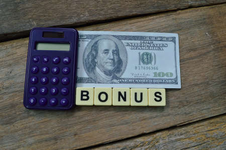 Top view of calculator, money banknote and square letters with text BONUS.の写真素材