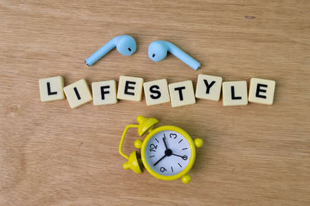 Top view of clock, earphones and square letters with text LIFESTYLE.の写真素材