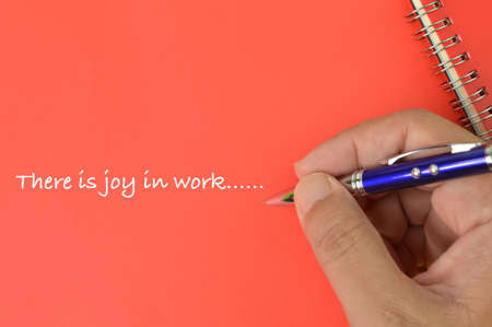 Hand holding pen and writing text THERE IS JOY IN WORK.の写真素材