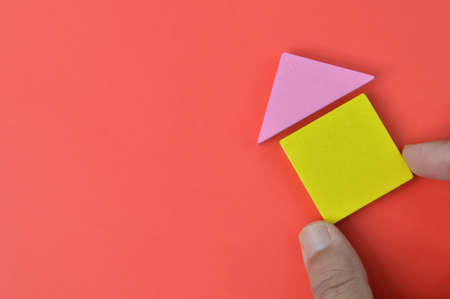 Hand holding house building blocks over red background. Real estate concept.の写真素材