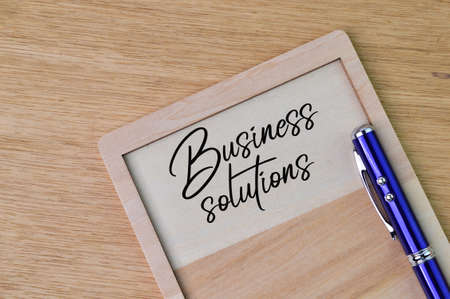 Pen and wooden board written with text BUSINESS SOLUTIONS.の写真素材