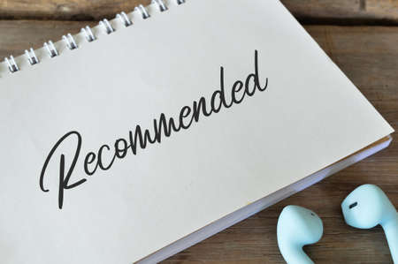 Earphones and notebook written with text RECOMMENDED.