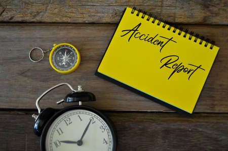 Top view of compass, clock and notebook written with text ACCIDENT REPORT.の写真素材