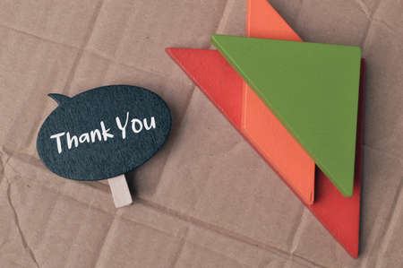Wooden tag written with text THANK YOU over cork board background.の写真素材