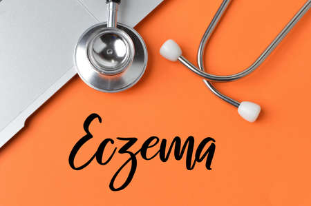 Stethoscope and notebook over orange background written with ECZEMA.の写真素材
