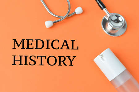 Hand sanitizer, stethoscope over orange background written with MEDICAL HISTORY.の写真素材
