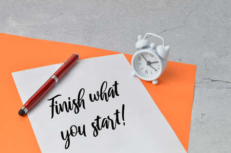 Pen, clock and white paper written with FINISH WHAT YOU START!.の写真素材