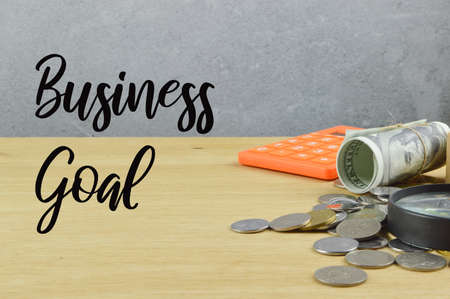 Coins, money banknote, calculator on the table written with BUSINESS GOAL.の写真素材