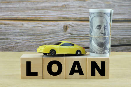 Money banknote, toy car and wooden cubes written with LOAN.の写真素材