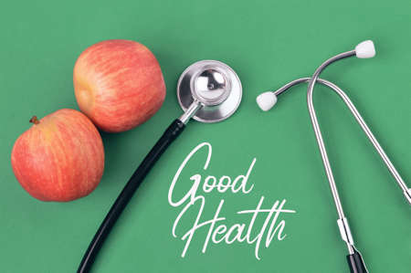 Stethoscope and apples over green background written with GOOD HEALTH.の写真素材