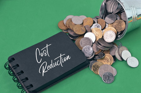 Coins and notebook written with COST REDUCTION.の写真素材