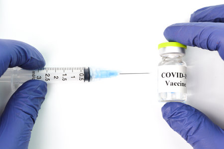 Hand holding Covid-19 bottle vaccination and syringe over white background.の写真素材