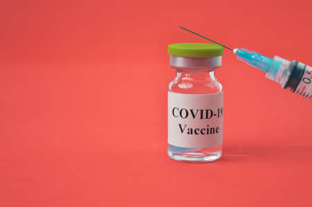 Syringe and Covid-19 bottle vaccination over red backgroundの写真素材
