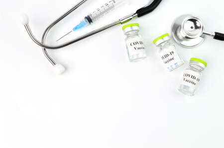 Syringe, stethoscope and Covid-19 bottle vaccination over white background.
