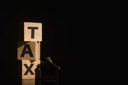 Toy house and wooden cubes with word TAX.の写真素材