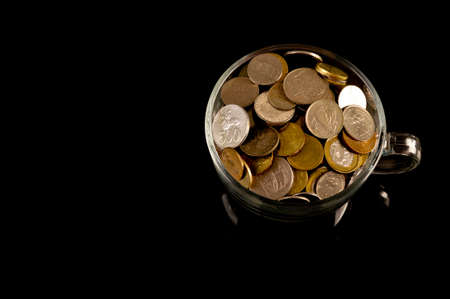 Bunch of coins in a glass cup on the table over red background