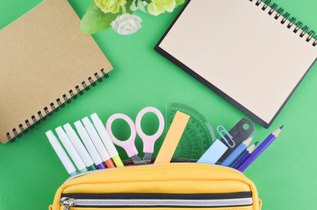 Flat lay view of stationery tools over green background with copy space.