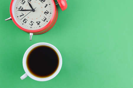 Alarm clock and a cup of coffee over green backgroundの写真素材