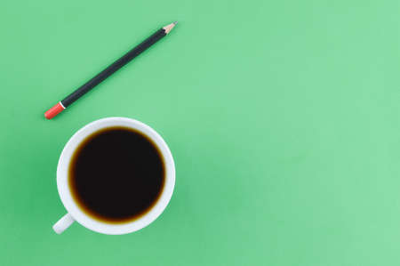 A cup of coffee and pencil over green backgroundの写真素材