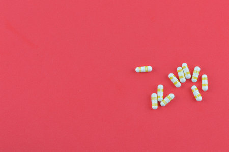 Top view of pill capsules over red background.
