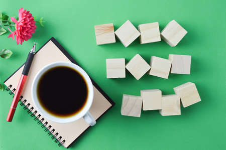 Top view of wooden blocks and a cup of coffee over green background.の写真素材
