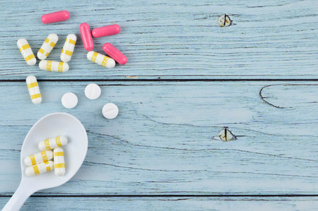 Pills and spoon over wooden background with copy space.の写真素材