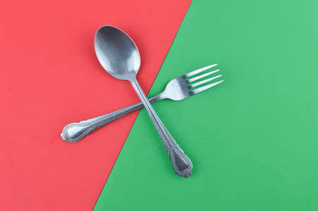 Spoon and fork over green and red backgroundの写真素材