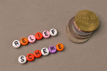 Top angle view of coins and alphabet beads with text RELIEF SCHEME.