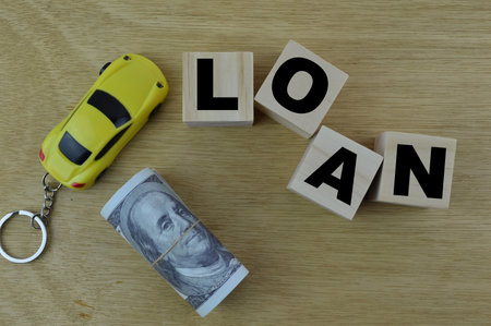 Top view of toy car, money banknote and wooden cubes written with LOANの写真素材